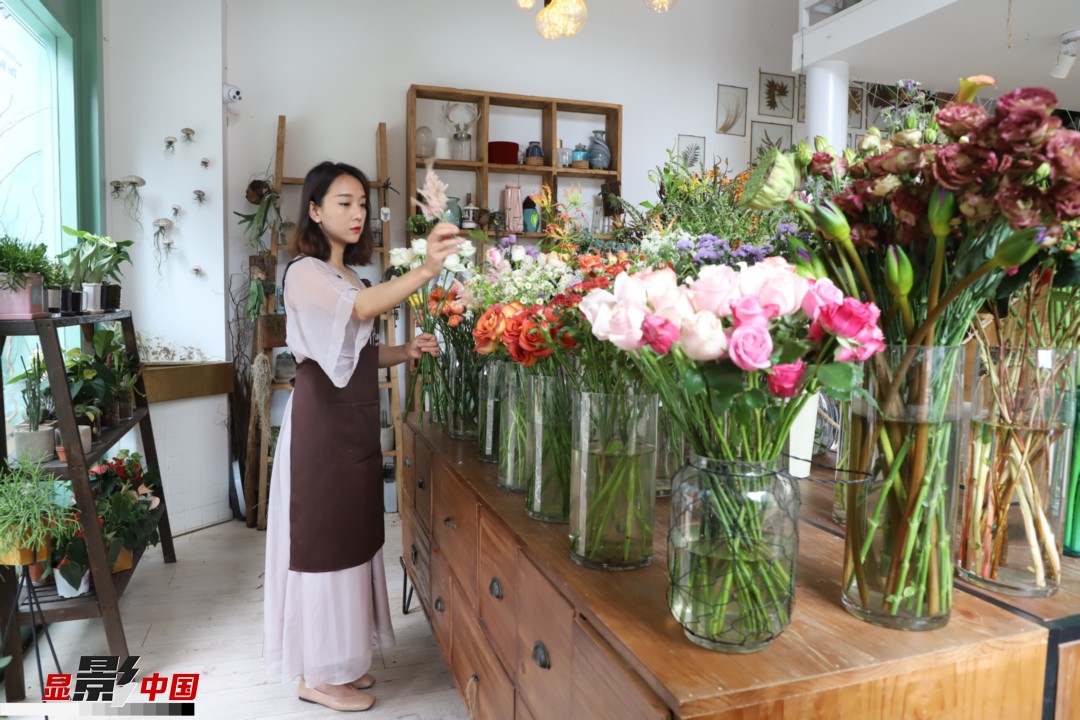 王黎媛是一名河南姑娘，在昆明念完大學(xué)后，就再也舍不下春城的藍天陽光、青山碧水，更舍不下這里的四時繁花，于是就干脆留了下來，成了一名媒體人。2017年的時候又毅然辭去工作，創(chuàng)業(yè)開起了花店，成了都市里的一名“花房姑娘”。圖為王黎媛在自己的花店中整理鮮花。新華網(wǎng) 周亞平/攝 念新洪/文